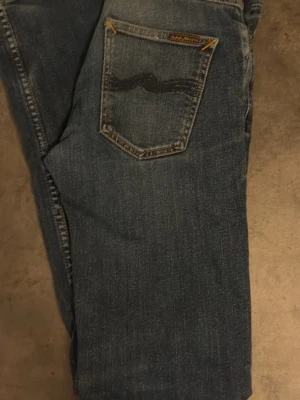 Blå Nudie Jeans - Säljer ett par blå Nudie Jeans med snygga slitningar. Storlek W29 L32. Skriv vid frågor eller funderingar. 