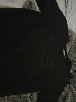 Svart sweatshirt med broderad tiger - Säljer en svart sweatshirt med en stor broderad tiger på bröstet. Tröjan har rund halsringning och långa ärmar. Materialet ser ut att vara mjukt och bekvämt, perfekt för en avslappnad stil. Passar dig som gillar stilrena plagg med en twist.