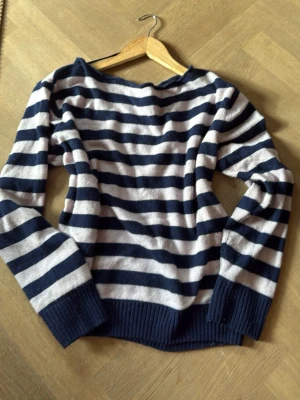 Randig stickad tröja från Subdued - Randig stickad tröja från Subdued i marinblått och baby rosa. Tröjan har långa ärmar, breda ribbade muddar och en klassisk rund halsringning. Perfekt för dig som gillar en avslappnad och cool stil.