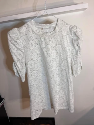 Vit spetsblus M - Säljer en söt vit genomskinlig blus från Kappahl i spets med puffiga korta ärmar och rund halsringning. Använd ca 2 gr
