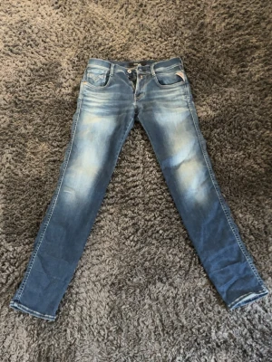 Replay jeans   - Säljer ett par blå slim fit jeans med snygga slitningar och tvättade detaljer. Klassisk femficksmodell med knappgylf och kontrastsömmar.  Materialet är troligtvis bomull med lite stretch. W29 L32