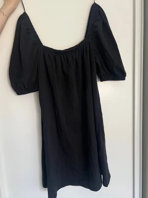 Svart puffärm klänning från H&M - Säljer en svart klänning från H&M med puffärmar och tunna axelband. Klänningen har en rak passform och är kort i modellen. Perfekt för dig som gillar en enkel men trendig stil.