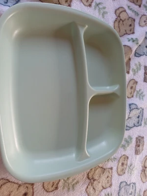 Grön plast tallrik med fack - Säljer en ljusgrön plasttallrik med tre fack, perfekt för att separera olika maträtter. Tallriken är tillverkad i Spanien och har en modern, rundad form. Passar bra till picknick, lunch eller middag. Enkel att rengöra och praktisk att använda.