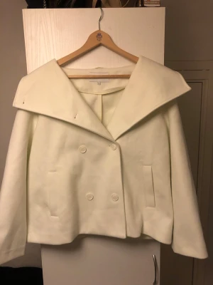 Vit kappa i storlek 42 från BUBBLEROOM - Jätte vacker kappa från BUBBLEROOM. Kappan är i storlek 42/XL och i färgen créme vit. Jackan har varit använd en gång. Jag säljer jackan eftersom den är lite för stor på mig. Kappan är i väldigt bra skick. Kappan har ett väldigt liten fläck på kragen som inte alls syns eftersom jag har tvättat bort det. Kappan passar perfekt inför våren och hösten. Det originala priset på kappan är 800kr. Meddela mig vid frågor och priset kan gärna diskuteras! 
