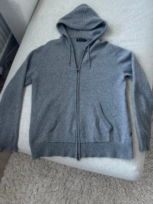 Grå Kashmir Zip från Riley - Grå stickad kofta från Riley med dragkedja framtill. Riktigt bra passform. Pris ej ristat i sten om snabb affär. Kontakta vid ytterligare frågor