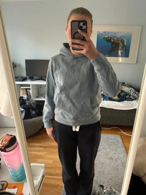 Blå hoodie med huva och ficka - Säljer en enkel blå hoodie med huva och stor magficka. Tröjan har en klassisk passform och är gjord i mjukt bomullsmaterial. Perfekt för chill dagar och passar till det mesta. Inga synliga loggor eller mönster.