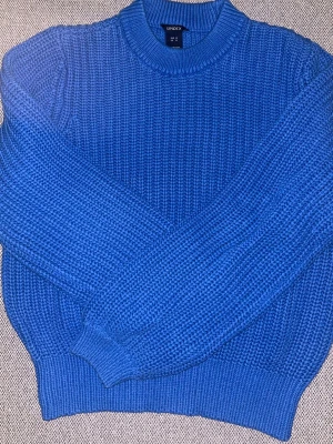 Blå stickad tröja från Lindex - Blå stickad tröja från Lindex med grovstickad struktur och rund halsringning. Tröjan har långa ärmar och ribbade muddar vid ärmslut och nederkant.💙