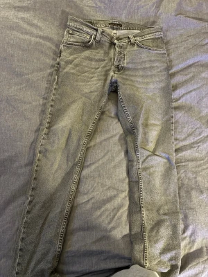 Nudie jeans - Ljusgrå Nudie jeans lite slitna nere vid fötterna(archive), storlek 30:30. Model grim trim, mitt pris är 400kr. Generellt riktigt feta jeans
