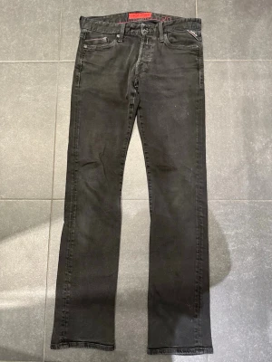 Svarta jeans från Replay - Tjena säljer ett par Snygga svarta jeans från Replay med raka ben och klassisk femficksdesign. Jeansen har diskreta kontrastsömmar och Replay-logga vid fickan. Perfekta för en stilren och avslappnad look.