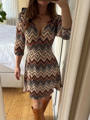 Mönstrad missoni style klänning - En klänning i missoni style med knyt i midjan. Perfekt för att tajta åt runt midjan. 