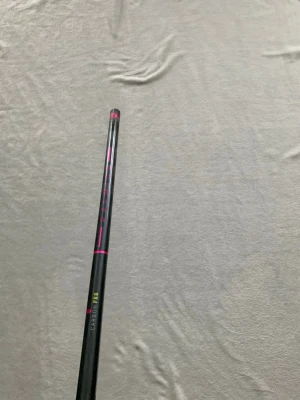 Salming Carbon Pro innebandyklubba - Säljer en svart Salming Carbon Pro innebandyklubba med rosa och gula detaljer. Skaftet är tillverkat i kolfiber och har ett greppvänligt handtag med vitt lindat grepp. Perfekt för dig som vill ha lätt och stabil klubba till innebandy.