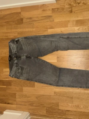 Grå jeans Replay Anbass - Säljer ett par gråa jeans från Replay, modell Anbass. De har smal passform. Jeansen är tillverkade i mjukt denimtyg och har snygga slitningar för en trendig look.