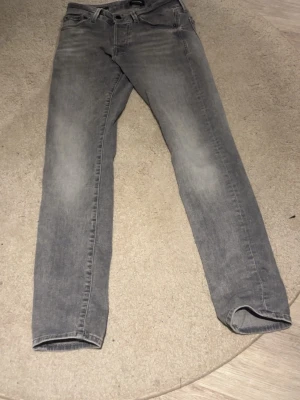 Grå slim fit jeans från Jack & Jones - Säljer ett par gråa slim fit jeans från Jack & Jones, modell Glenn. Jeansen har klassisk femficksdesign, knappgylf och är tillverkade i ett mjukt denimtyg. Perfekta för dig som gillar en smalare passform och stilren look.