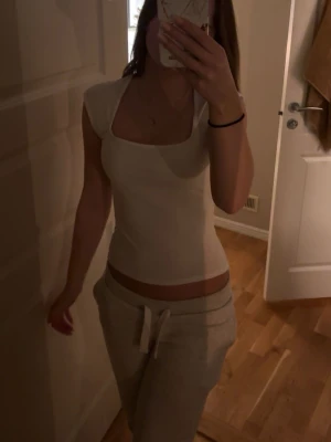 Vit tight topp från Gina Tricot - Säljer en vit, tight topp från Gina Tricot med fyrkantig ringning och korta ärmar. Toppen är enkel och stilren, perfekt att matcha med olika outfits. Tillverkad i mjuk bomullsmix för skön känsla. Nästan helt ny!