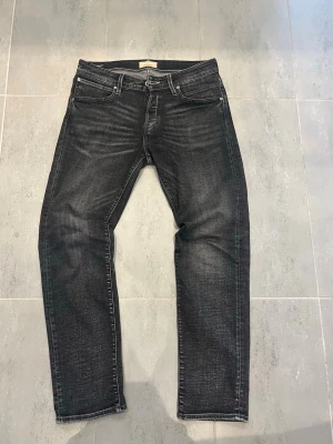 Svarta jeans ifrån Jack&jones - Snygga svarta slim fit jeans med klassisk femficksdesign. Jeansen har en något tvättad look och raka ben. Perfekta för en avslappnad och trendig stil.