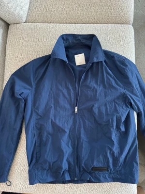 Blå jacka från Sandro Paris - Lätt fodrad blå jacka från Sandro. Mycket bra skick. Storlek står ej men är M, se sista två bilderna för mått. Nypris ca 5000 kr.