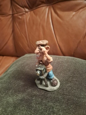 Charmig figurin Fotograf – Karikatyr / Retro stil - Säljes: Charmig och detaljrik figurin föreställande en klassisk fotograf med gammaldags kamera på stativ. Figurinen är gjord i en lekfull karikatyrstil med härliga ansiktsuttryck och fina detaljer. Materialet påminner om träsnideri men är sannolikt ett robust kompositmaterial/resin som ger en fin tyngd och struktur. Ett måste för kamerasamlaren eller som en rolig inredningsdetalj på skrivbordet eller i bokhyllan!Motiv: Fotograf med bälgkamera. Skick: Mycket gott skick.
