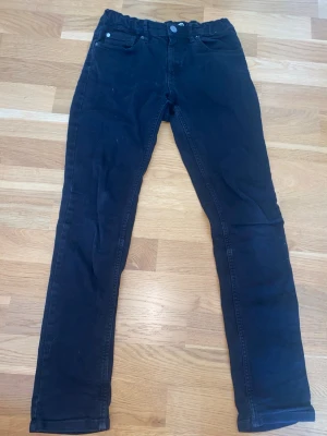 Svarta manchesterbyxor med femficksdesign - Säljer ett par svarta manchesterbyxor med klassisk femficksdesign och raka ben. Byxorna har knapp och dragkedja framtill samt diskreta sömmar. Perfekta för dig som gillar en stilren look och mjukt material. Inga fläckar som inte går bort i tvätt!! 