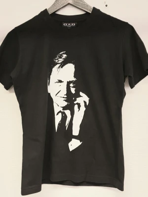 Olof Palme dam t-shirt med tryck - Cool svart t-shirt från DAD Sportswear med ett stort vitt Palme tryck på framsidan. Klassisk rund halsringning och korta ärmar. Storlek Smal (dam)