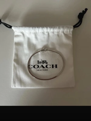 Armband från Coach - Stilrent och tunt armband i silverfärg från Coach. Armbandet har en enkel, rund design och sitter som en bangle. Perfekt för dig som gillar minimalistiska accessoarer och vill ha något klassiskt till din look. Levereras med originalpåse från Coach. Ordinarie pris 970kr, köpt zalando