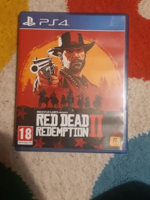 Red Dead Redemption 2 till PS4 - Red Dead Redemption 2 till PlayStation 4. Omslaget är rött och orange med en cowboy som håller en revolver, och flera silhuetter av ryttare i bakgrunden. Spelboxen är av plast och har åldersmärkning 18+.