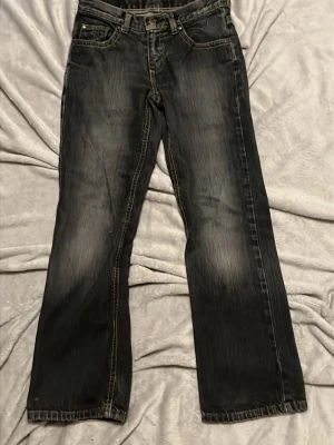 Svarta bootcut jeans - Säljer ett par svarta bootcut/straight jeans med kontrastsömmar. Klassisk femficksdesign och snygga bakfickor. Perfekta för dig som gillar en avslappnad och trendig look. Materialet är denim.