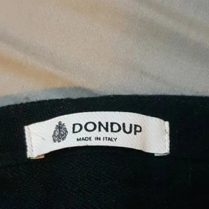 Svarta mjukisbyxor från Dondup - Ett par svarta bomullbyxor från Dondup, tillverkade i Italien. Byxorna har rak passform och är gjorda i ett mjukt och bekvämt material som passar perfekt för en chill look. Klassisk design utan synliga detaljer eller loggor på benen.