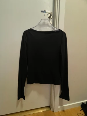 Svart långärmad topp - En enkel och stilren svart långärmad topp med rak passform. Perfekt att matcha med jeans eller kjol för en clean look. Materialet känns mjukt och stretchigt, vilket gör den bekväm att bära hela dagen.