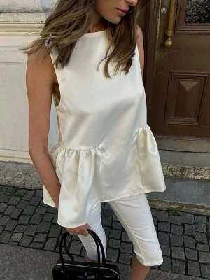 Vit ärmlös satinblus med volang NA-KD  - Snygg vit ärmlös blus i glansigt satinmaterial med volangdetalj. Helt ny i förpackning 