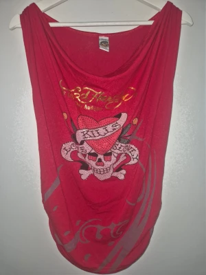 Ny röd Ed Hardy klänning eller lång topp! Storlek One Size 36-42 - Cool röd linnetopp från Ed Hardy med stort tryck av dödskalle, hjärta och texten 'Kills Love Slowly' framtill. Toppen har ett avslappnat fall och bred urringning. Materialet är mjukt och lätt, perfekt för varma dagar. Stretchig och många snygga detaljer!                        Djur och rökfritt hem.                                                     Ny, endast lappar borttagna!                                       Djur och rökfritt hem.     One size fits all 36-42