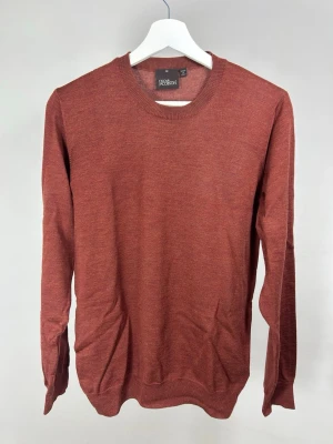 Oscar Jacobson Stickad Tröja Rostbrun | M - Snygg rostbrun stickad tröja från Oscar Jacobson. Tröjan har rund halsringning, långa ärmar och är tillverkad i Italien. Perfekt för dig som gillar stilrena och klassiska plagg i mjukt material.