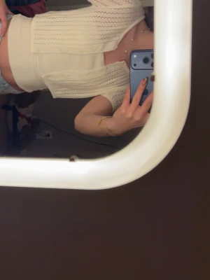 Vit croppad stickad bolerotopp - Säljer en söt vit croppad kofta/topp med korta ärmar och öppen front. Toppen är stickad i ett luftigt mönster och passar perfekt över ett linne eller crop top. Enkel att styla till jeans eller kjol för en trendig look.