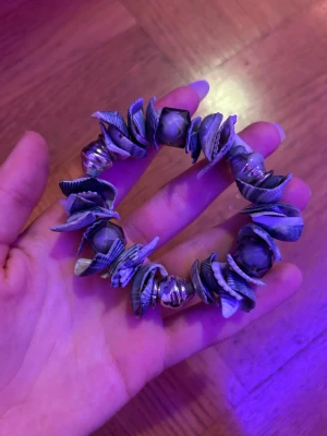 Armband med snäckor och pärlor - Unikt armband med blågrå snäckor och silvriga pärlor. Armbandet har elastisk tråd och pärlor i metall-look som varvas med snäckbitar för en cool strandkänsla. Perfekt accessoar för dig som gillar boho-stil och naturliga material.