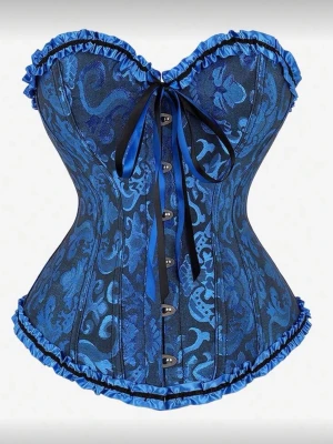 Blå mönstrad korsett med rosett - Säljer en snygg blå korsett med svart och blått blommönster, dekorerad med volangkant och en stor satinrosett framtill. Korsetten har metallknappar framtill och markerad midja för en klassisk siluett. Materialet är glansigt och känns lyxigt.