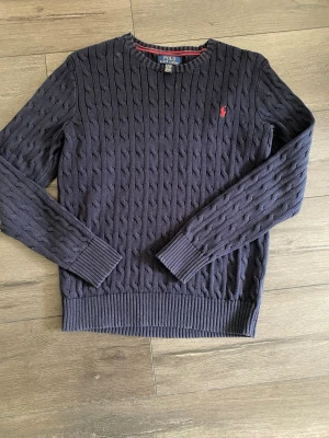 Mörkblå kabelstickad tröja Polo Ralph Lauren - Säljer denna populära  tröjan från Ralph Lauren. Storlek XL BARN så den sitter som en S/M Knappt använd, skriv vid frågor. 