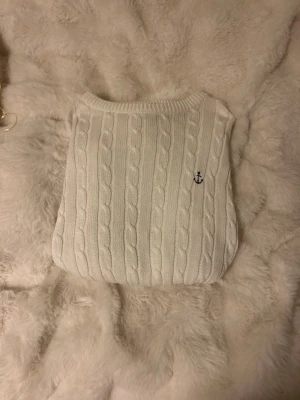 Vit kabelstickad tröja med ankare - Kabelstickad vit tröja med rund hals och ett litet broderat ankare på bröstet. Tröjan har långa ärmar. Perfekt för en klassisk och stilren look, passar till jeans eller kjol. Den är lite oversized och jag säljer eftersom den var förstor🤗