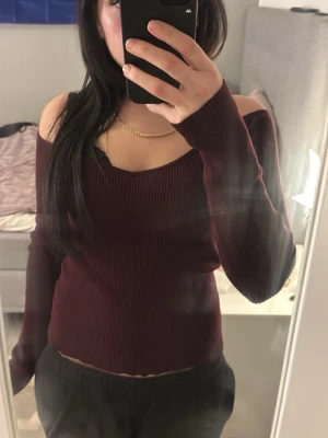 Vinröd off shoulder stickad topp H&M - Säljer en vinröd ribbstickad off shoulder topp från H&M. Tröjan har långa ärmar, djup urringning och sitter tight. Perfekt för dig som vill ha en trendig och bekväm stickad topp med snygg passform. Hund finns i hemmet därav är den lite hårig. 