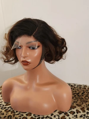 Brun lockig peruk med sidbena - Snygg svartbrun peruk med mjuka lockar och sidbena. Peruken har naturlig glans och volym, perfekt för att skapa en trendig look. Passar dig som vill ha en kortare frisyr med mycket rörelse. Materialet är 100% human hair, äktahår.