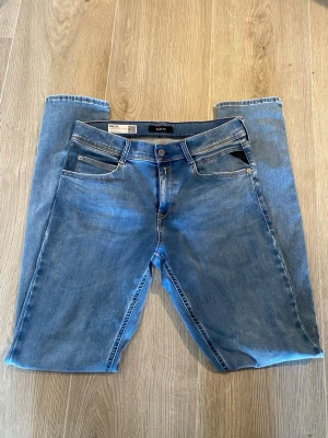 Blå raka jeans från replay - Säljer ett par klassiska blå jeans från Jack & Jones med rak passform. Jeansen har fem fickor, ljus tvätt och snygga sömdetaljer på bakfickorna. Tillverkade i bomull med en skön stretch. Perfekta till vardagslooken! Det är en liten fläck vid bak sidan men den går bort vid en grövre tvätt. Det är barn storlek 168 cm 