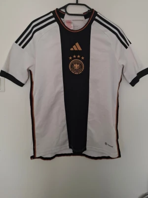 Tyskland 2022/23 tröja - Tyskland tröja från säsongen 2022/23. Storlek 176/S. Tröjan är i bra skick förutom stygnen (bild 6 och 7). Äkta!