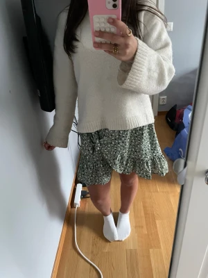 Grön omlottkjol med volang - Superfin grön-mönstrad kort omlottkjol med svartvitt prickigt mönster och volangkant. Kjolen har en knytning i midjan och är gjord i ett lätt och skönt material, perfekt för varmare dagar. Passar dig som vill ha en trendig och bekväm look. Den perfekt till sommaren!!☀️Lägg gärna bud!