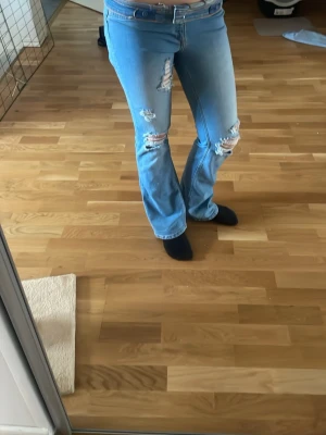 Ljusblå bootcut jeans med slitningar - Super snygga low waisted bootcut jeans. De har en väldigt fin och trendig slitning på benen vilket ger outfiten en cool look. Midjan har vikts ner till low waisted men kan även användas som high waisted om man föredrar det. De är super snygga i pass formen och väldigt trendiga. De ger liv till en tråkig outfit och matchar de flesta kläderna❤️❤️ storlek: S