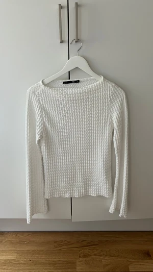 Vit långärmad topp med struktur - Säljer en vit långärmad topp med våfflad struktur och rund hals. Tröjan har en lätt stretchig känsla och raka ärmar. Perfekt att styla till jeans eller kjol för en clean look.