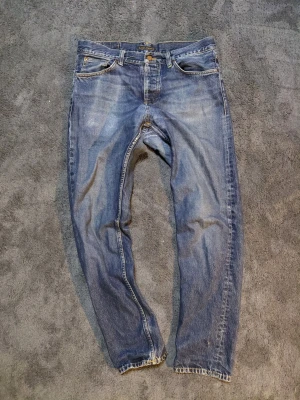 Mörkblå Nudie Jeans - Ett par riktigt snyggt slitna nudie jeans i modellen grim tim(tror jag). Kom gärna med frågor eller prisförslag!