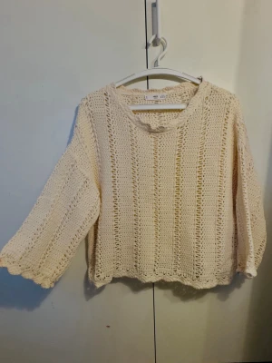Beige stickad tröja  - Säljer en beige stickad tröja från MNG Casual i storlek XS. Tröjan har ett luftigt, virkat mönster, rund halsringning och vida trekvartsärmar. Perfekt för lager på lager och ger en avslappnad vibe till din outfit.