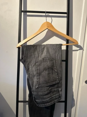 Grå slitna jeans - Säljer ett par grå jeans med coola slitningar och tvättad look. jeansen har tydliga slitdetaljer på både framsidan. Perfekta för en avslappnad streetstil och passar till det mesta. Materialet är klassisk denim i bomull. Storlek 30/32
