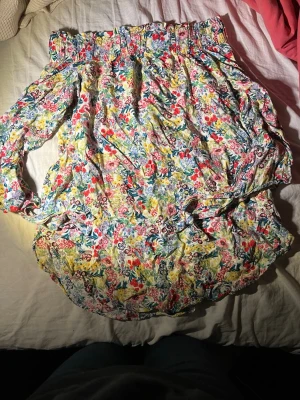 Blommig offshoulder blus i pastell - Söt offshoulder blus med färgglatt blommönster i pastellfärger som rosa, gul, blå och grön. 