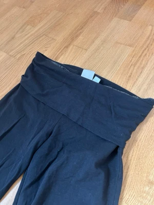 Svarta bootcut leggings - Säljer ett par svarta leggings med bootcut-ben. De är stretchiga och bekväma, perfekta till en avslappnad stil. Materialet är mjukt och följsamt, troligtvis bomullsblandning. Passar dig som gillar enkel och clean look.