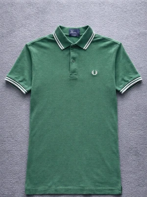 Fred Perry Polo Shirt – Classic British Mod Style – S - Klassisk Fred Perry polo shirt i grön färg med den ikoniska laurel wreath-loggan broderad på bröstet.  En tidlös piké som passar perfekt för British mod / terrace style eller en clean casual outfit.  Detaljer: • Fred Perry • Storlek S • Mycket bra skick • Klassisk polokrage med kontrastdetaljer • Broderad logotyp på bröstet • Grön färg  Perfekt till jeans, chinos eller shorts.  📦 Skickas snabbt 💬 Hör gärna av dig