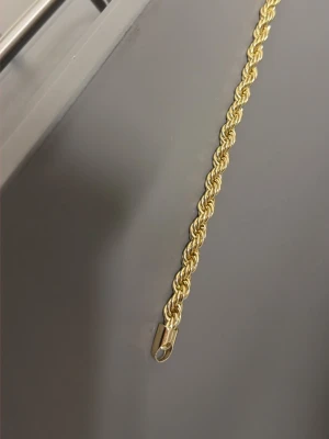 Guldfärgat tvinnat halsband - Snyggt guldfärgat armband med tvinnad kedja som ger en exklusiv känsla. Halsbandet har en klassisk design och är tillverkat i metall med en glansig finish. Perfekt accessoar för att lyfta din outfit.